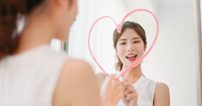 Một người phụ nữ mỉm cười, thể hiện lòng yêu bản thân và sự trân trọng chính mình trong cuộc sống.
