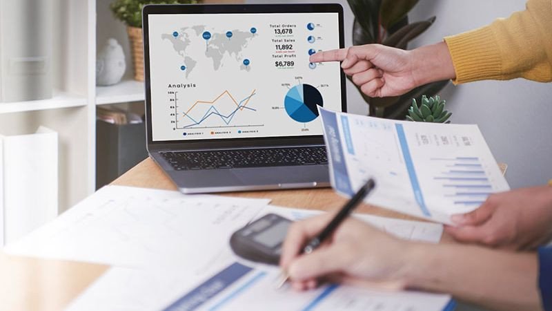 Hình ảnh bàn làm việc với máy tính và sổ sách, thể hiện việc lập kế hoạch ngân sách
