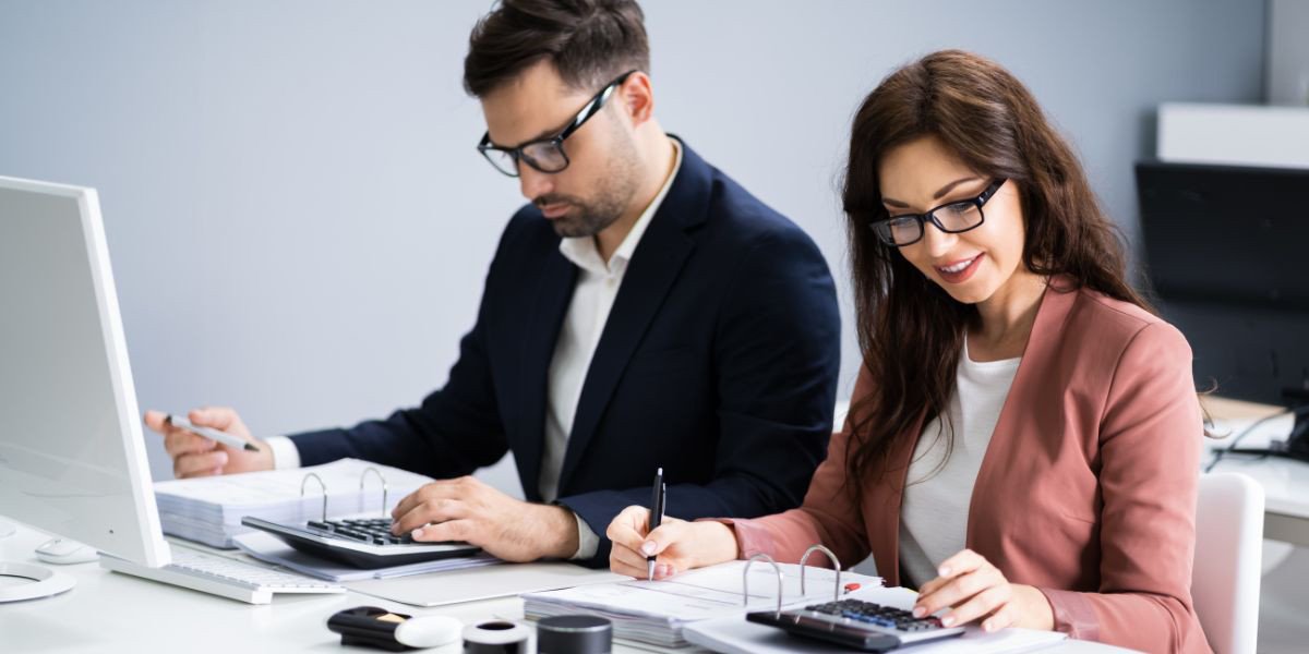 Kế toán viên làm việc chăm chỉ với giấy tờ và máy tính, thể hiện vai trò quản lý tài chính quan trọng của họ trong doanh nghiệp.